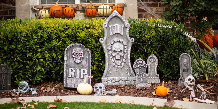 Scary Halloween yard ideas with creepy tombstones, skeleton props, pumpkins, and cobwebs creating a haunted graveyard scene.
