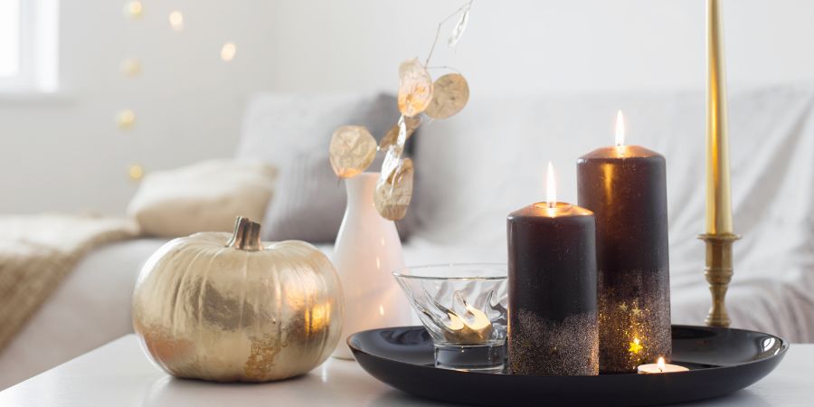 Halloween interior design with elegant black candles, a metallic gold pumpkin, and cozy minimalist accents for a chic seasonal look.