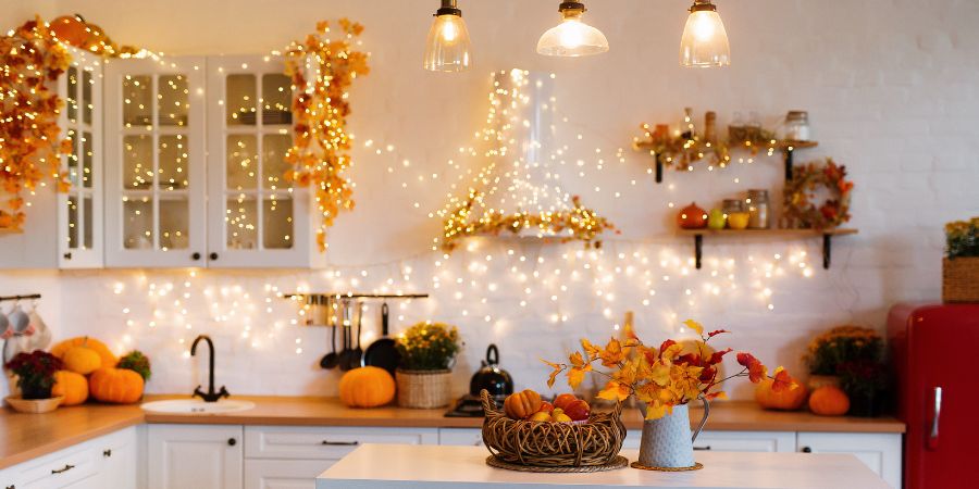 Best Halloween decorations in a cozy kitchen with twinkling string lights, pumpkins, and autumn leaves creating festive Halloween home decor and unique indoor decorating ideas.