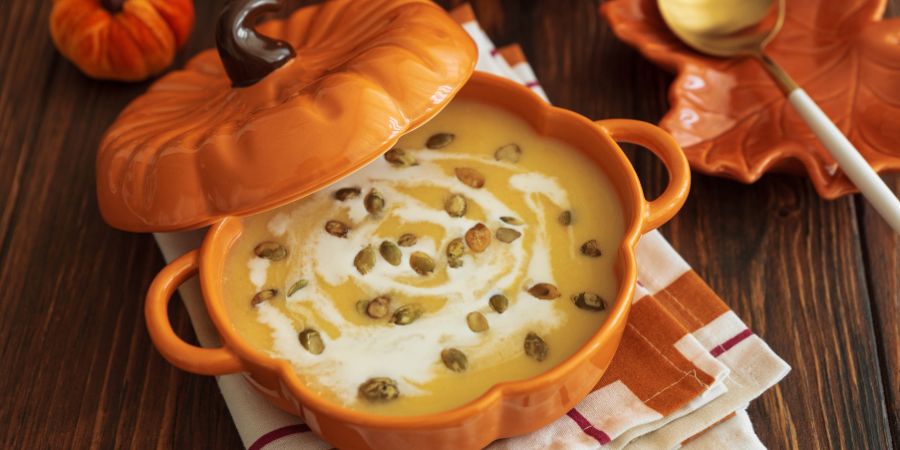 Halloween interior decorating with festive pumpkin-shaped soup bowl filled with creamy pumpkin soup, perfect for cozy fall dining.