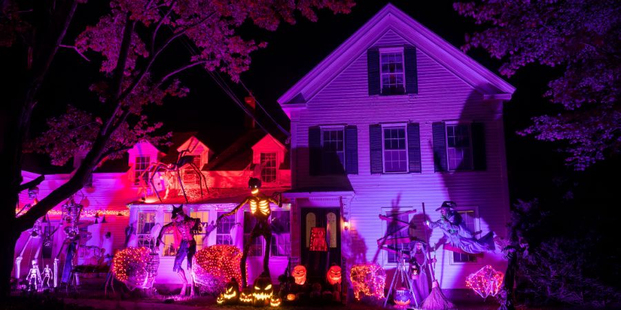 Halloween home decor taken to the next level with glowing skeletons, witches, jack-o’-lanterns, and dramatic purple lighting covering the entire house and yard.
