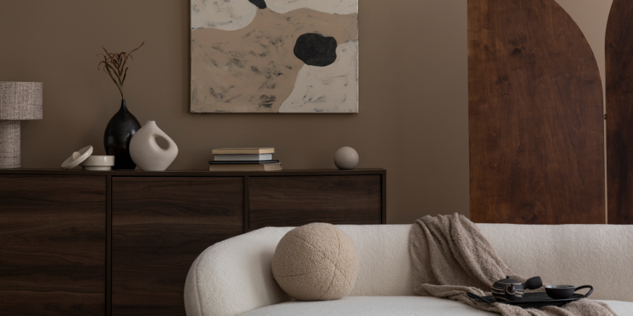Modern neutral living room design with curved sofa, wooden sideboard, abstract wall art, and cozy textures.