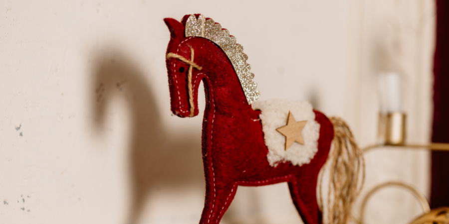 Red felt decorative horse ornament with gold star and textured details on a light background.