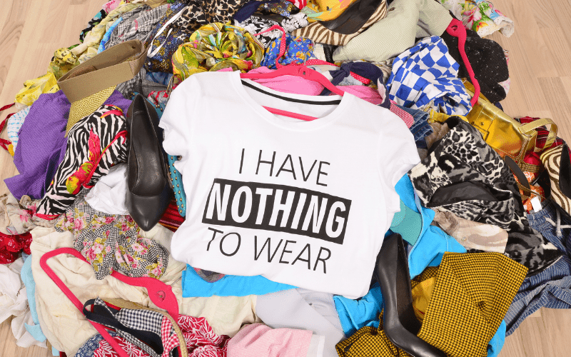 messy pile of clothes and shoes on floor, with shirt on top that reads "i have nothing to wear"