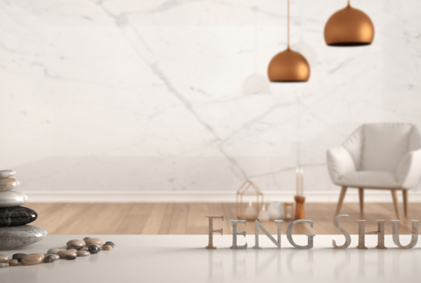 White table shelf with pebble balance and 3d letters making the word feng shui over empty room with marble wall, white armchair, candles and decor, zen concept interior design, 3d illustration