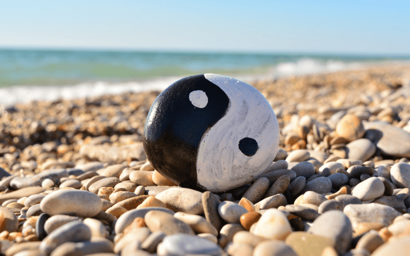 Feng Shui yin and yang symbol painted on rock on rocky beach