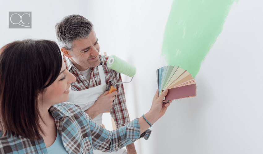 Man and woman deciding on wall paint color by looking at color swatches against white wall