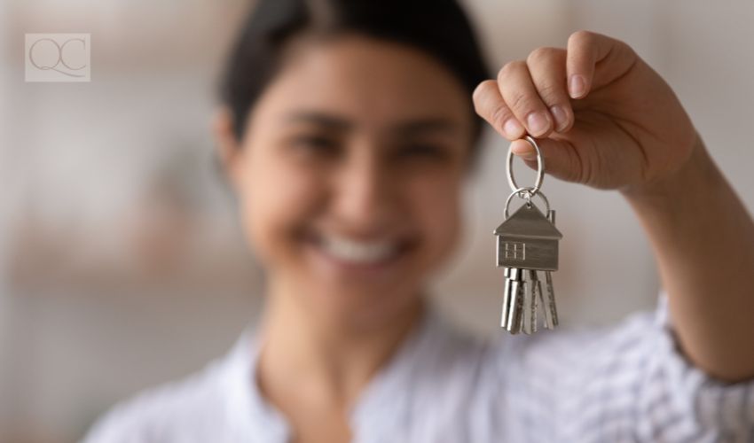 Focus on bunch of keys from house flat apartment in hand of smiling female. Blurred portrait of confident woman professional realtor offering new dwelling real estate unit to potential buyer.