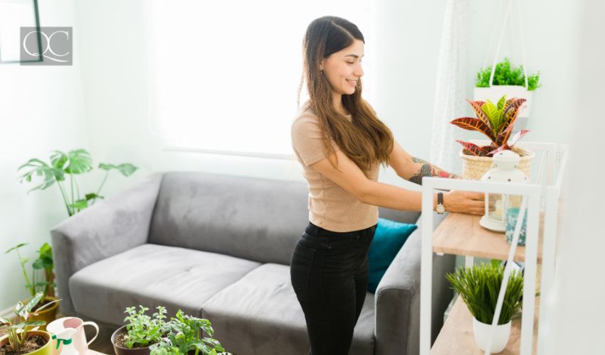 Happy young woman with a wellness lifestyle decorating her home with green plants to improve her positive mental health
