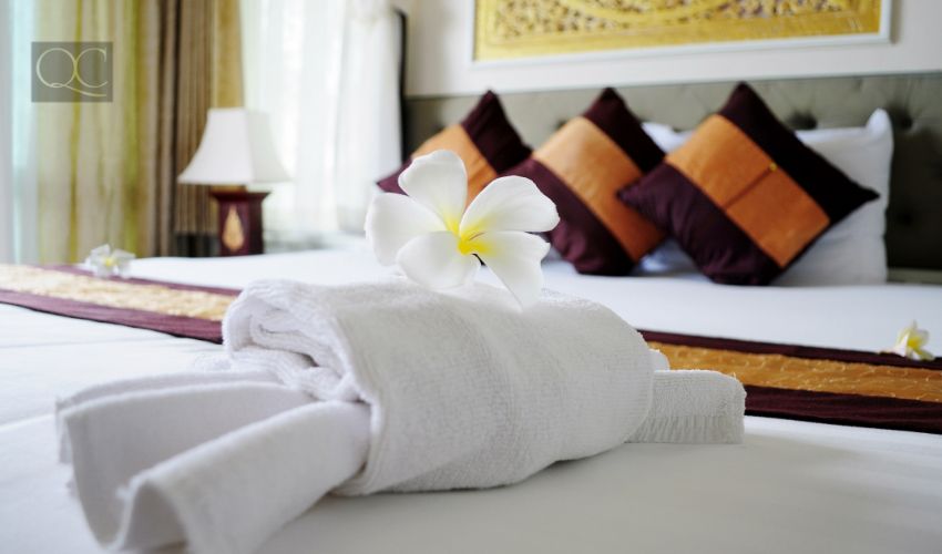 White towel in crab shape and a frangipani flower on white bed in relaxation bedroom of luxury boutique hotel
