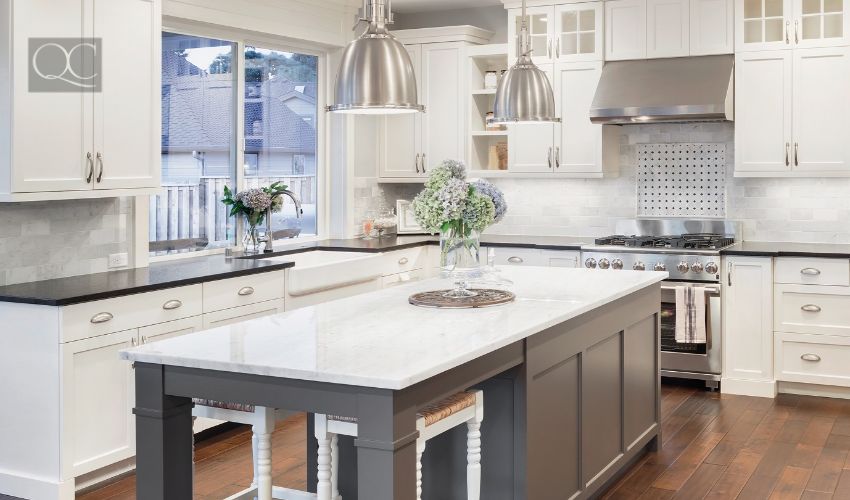 beautiful kitchen in luxury home with island, pendant lights, cabinets, and hardwood floors. tile back splash, stainless steel oven,range, and hood compliment the elegant features