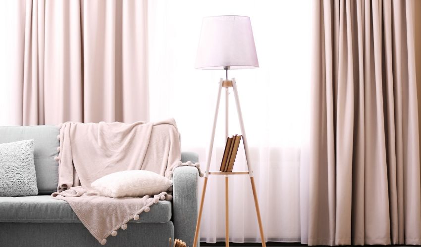 Comfortable sofa with lamp and book against window in the room. Home decor ideas.