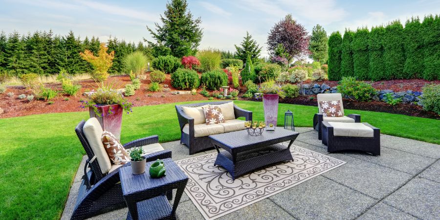 Impressive backyard landscape design. Cozy patio area with settees and table. Virtual design article.