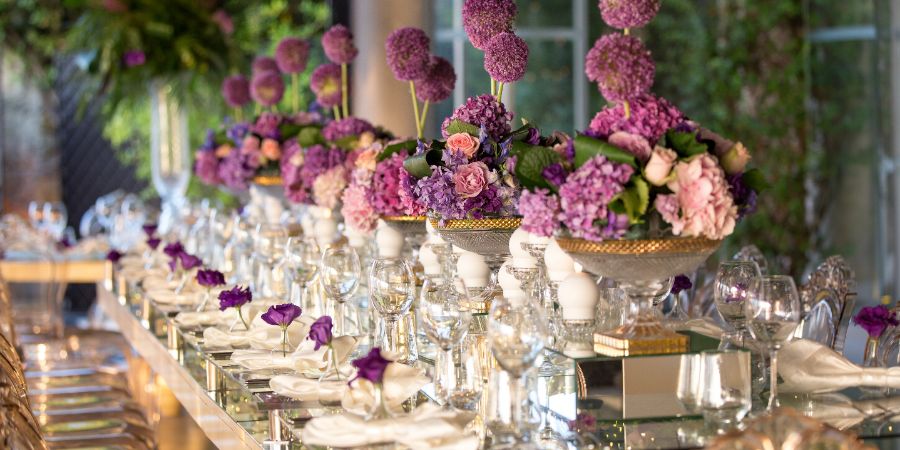 indoor wedding table with flowers candles and chandeliers. Event decor article.