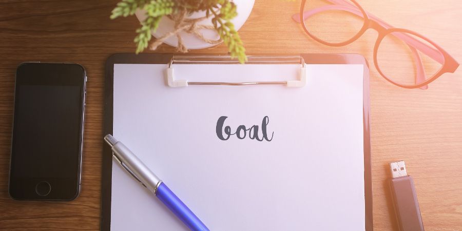 Business concept - Top view notebook writing Goal. How to set achievable goals article.