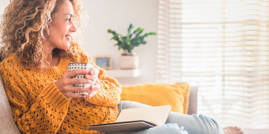 Woman have relax at home with cup of tea and book - reading activity for adult beautiful female people - enjoying quiet lifestyle indoor and long blonde curly hair - happy adult female indoor - people. Feng Shui article.